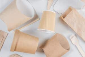 Emballages take-out écologiques: tasse à café nervurée en kraft, sacs et contenants bruns, avec fourchette et agitateur en bois.